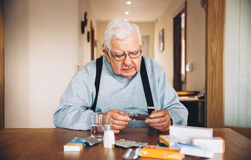 Älterer Herr mit Medikamentenpackungen