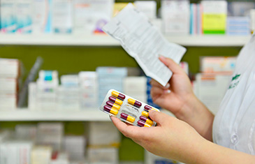 Apothekerin hält Arzneimittel und Beipackzettel in der Hand