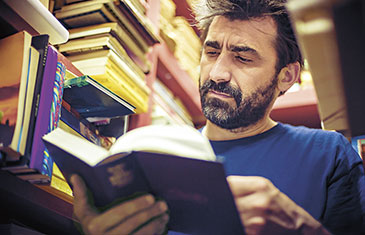 Mann liest in einer Bibliothek