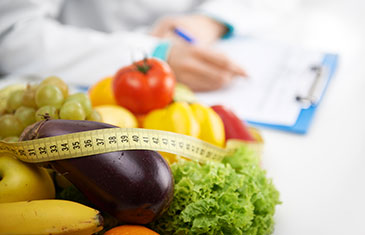 Ernährungsexperte mit Gemüse, Obst und Maßband im Vordergrund