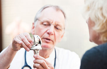 Arzt erklärt Patientin Funktionsweise eines künstlichen Gelenks