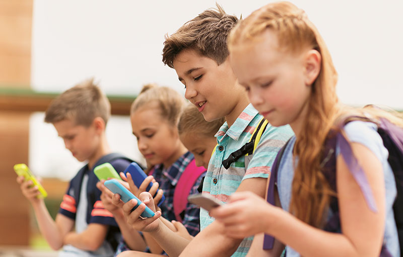 Schulkinder starren gebannt auf ihre Smartphones