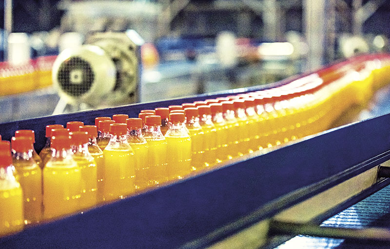 Mit gelber Flüssigkeit gefüllte Getränkeflaschen laufen über Band in Fabrik