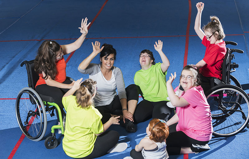 Kinder und Jugendliche mit Behinderung zusammen mit Trainerin in Sporthalle