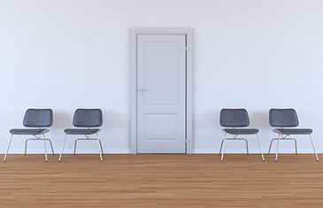 Leeres Wartezimmer mit vier Stühlen und verschlossener weißter Tür