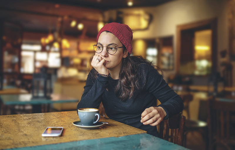 Junge Frau sitzt einsam im Kaffee