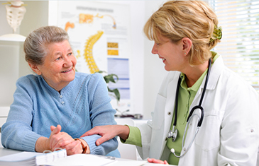 Foto von Ärztin, die vertrauensvoll mit älterer Patientin spricht