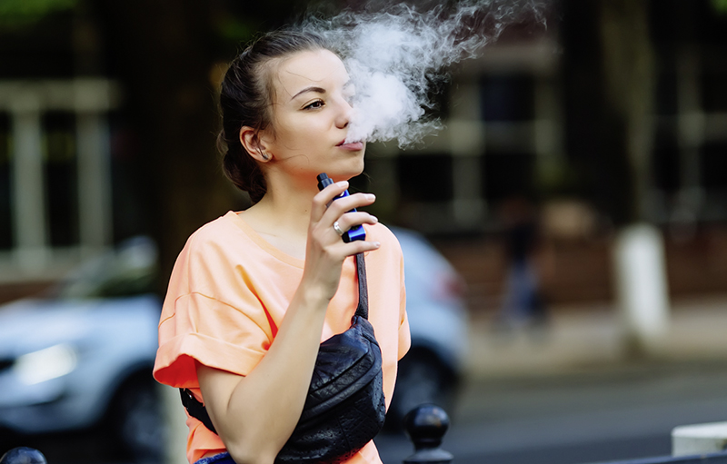 Foto von einer Jugendlichen, die eine E-Zigarette raucht