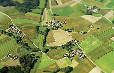 Foto einer ländlichen Region von oben. Viele Felder, ein paar Wälder und kleine Dörfer.