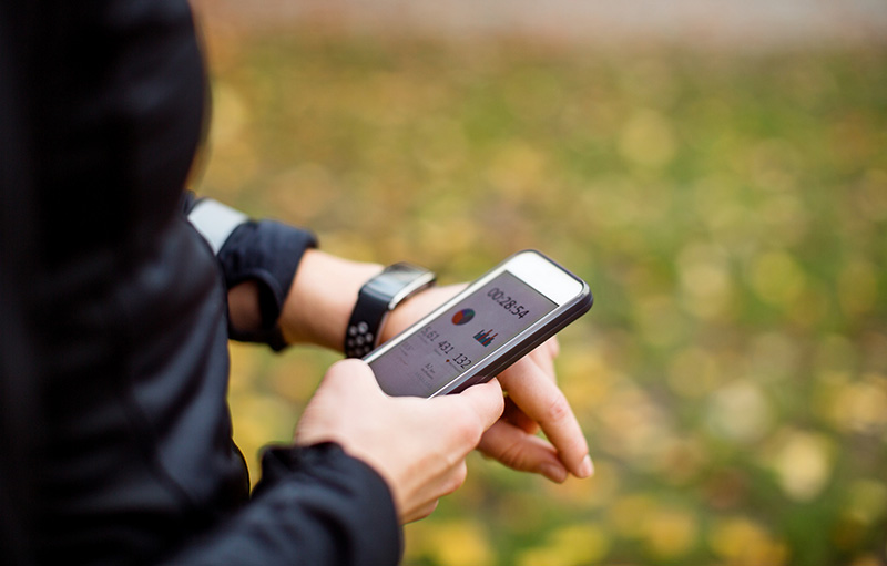 Foto von Person im Jogging-Outfit, die Daten auf Smartphone einsieht