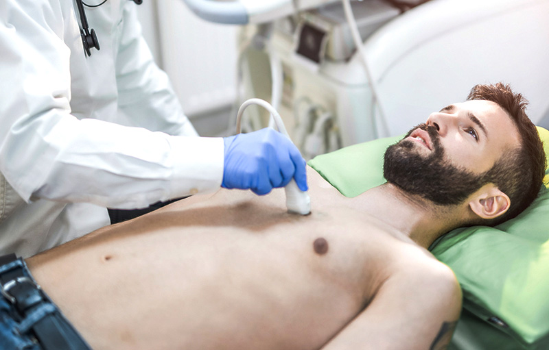 Foto von Arzt, der Ultraschall des Herzens bei einem jungen männlichen Patienten macht