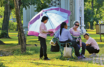 Foto von vier älteren thailändischen Frauen, die sich im Sommer an einer Parkbank treffen