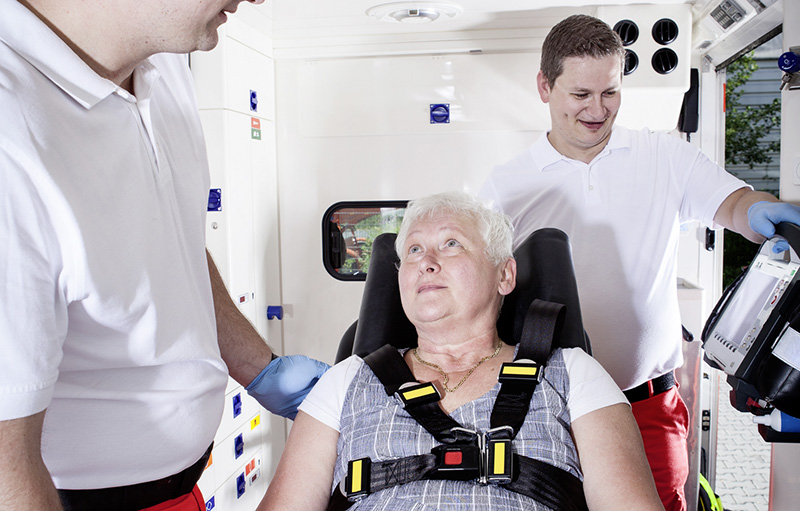 Foto einer älteren Frau im Rettungswagen in Begleitung eines männlichen Notfallteams