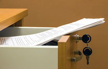Foto einer geöffneten Schublade mit Schlüssel, aus der ein Dokument hervorragt