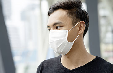 Foto eines jungen asiatischen Mannes mit weißem Mundschutz und schwarzem T-Shirt