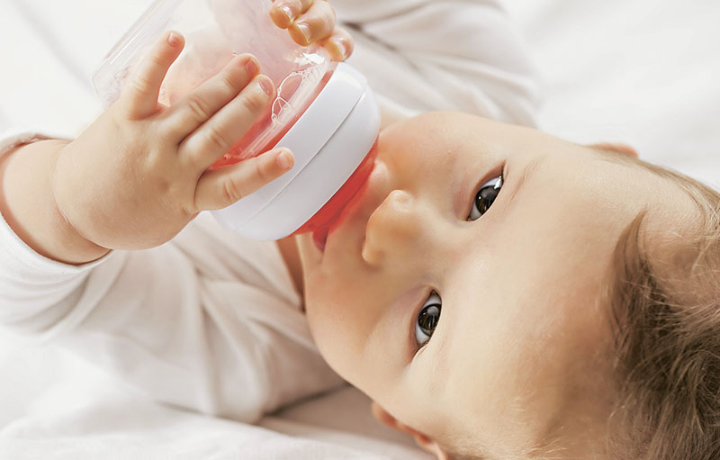 Foto eines Babys, das Tee aus dem Fläschchen trinkt