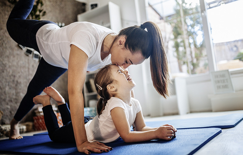 Foto einer jungen Mutter, die mit ihrem Kind zusammen Fitness auf der Matte macht