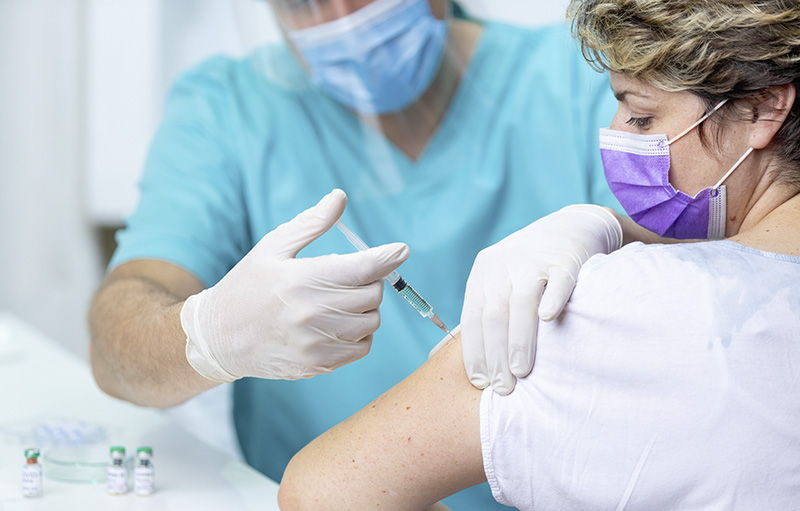 Foto einer Frau mit Maske, die von einem Mediziner mit Maske geimpft wird