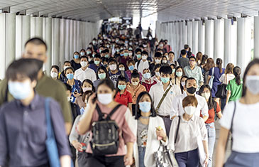 Foto von einer Menschenmasse asiatischer Herkunft mit Masken auf, die durch einen Durchgang läuft