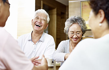 Foto von zwei japanischen Paaren höheren Alters, die zusammen fröhlich an einem Tisch sitzen