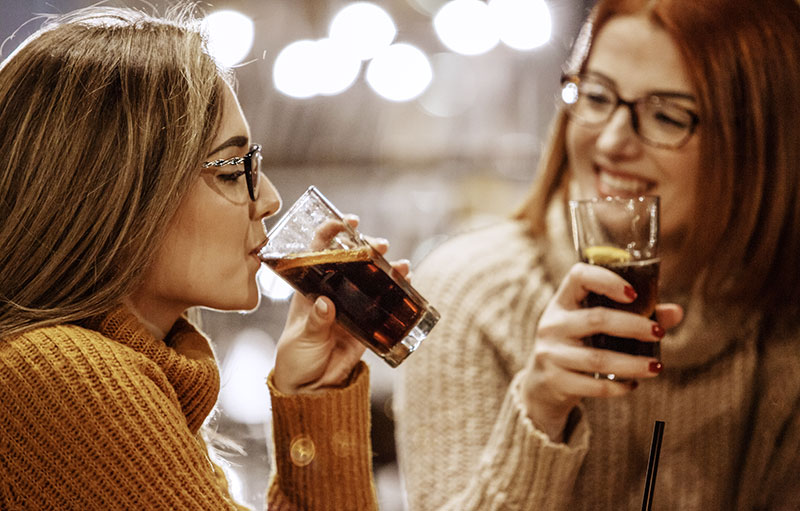 Foto von zwei jungen Frauen, die eine Cola trinken