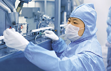 Bild eines Mitarbeitenden in Schutzkleidung und Maske bei der Arzneimittelproduktion