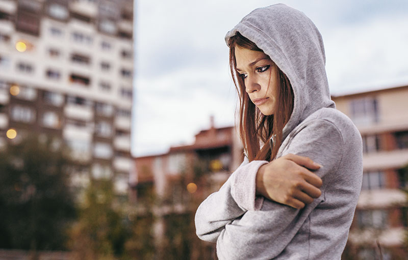 Traurig aussehende Teenagerin vo einem Hochhauskomplex