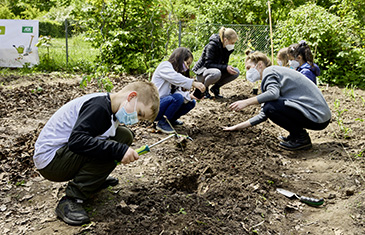 Foto der Zweitklässler Leo und Esma bei der Arbeit im Beet im Garten ihrer Schule in Laatzen. Dabei helfen Anne Müller (rechts) vom Verein Ackerdemia und Referendarin Franziska Florian.