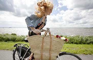 Foto einer Radfahrerin mit Rückenwind vor Küstenlandschaft