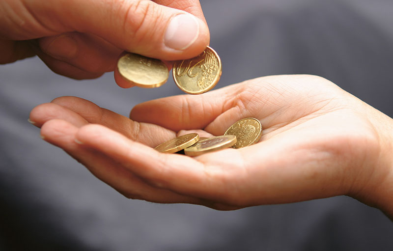 Foto von einer Hand, die in eine geöffnete darunter Kleingeld legt