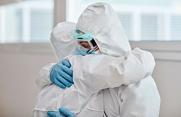 Foto von zwei Medizinern in Schutzkleidung, die sich umarmen