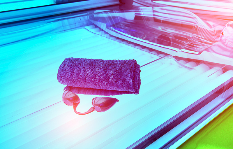 Foto von Kabine eines Solariums mit UV-Schutz-Brille und Handtuch