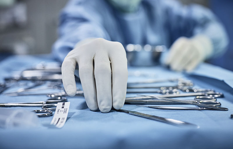 Foto von medizinischem Personal, das mit weißen Handschuhen auf einer sterilen Unterlage medizinische OP-Instrumente sortiert