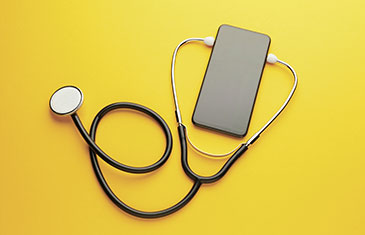 Symbolbild eines Smartphones, das mit einem Stethoskop verbunden ist. Beides liegt auf einem gelben Hintergrund.