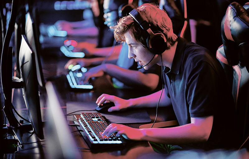 Foto eines Gamers, der sich in einem Gaming Center nach vorne über die Tastatur beugt
