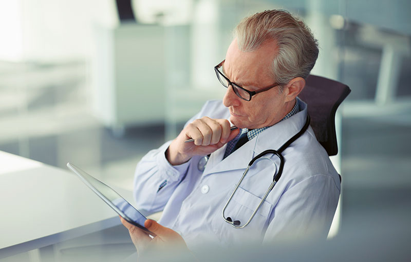 Foto eines Arztes, der auf ein Tablet blickt