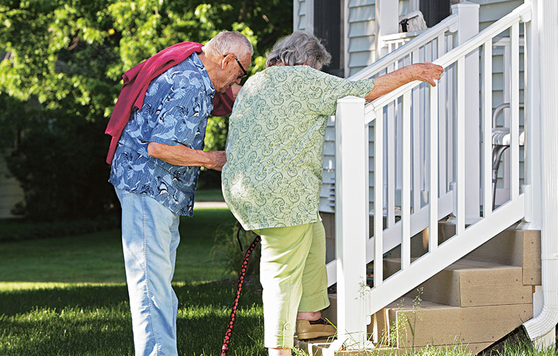 Foto von einem Seniorenpaar, das eine weiß gestrichene Treppe hochsteigt