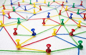 Foto von bunten Fäden, die zwischen farbigen Pinnnadeln gespannt sind wie ein Netzwerk
