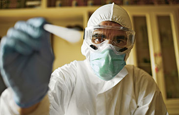 Foto einer männlichen Pflegekraft in Schutzanzug mit Schutzbrille und Mundschutz
