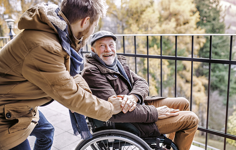 Foto eines dankbaren alten Mannes im Rollsthul, der auf einer Aussichtsplattform die Hand eines jüngeren Mannes hält
