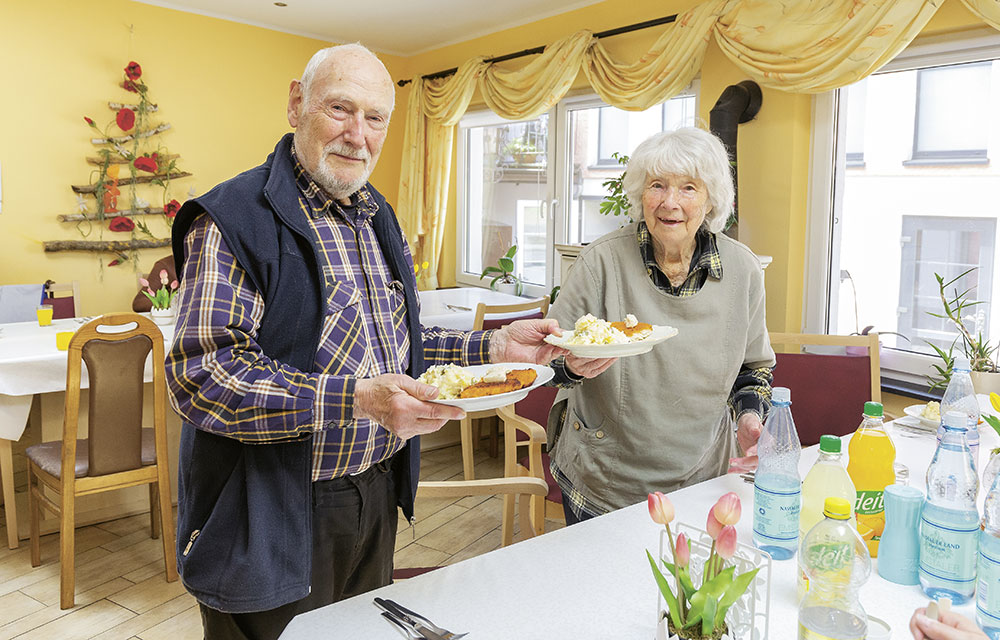 Foto von Horst und Ingeborg Hof, die ihre gefüllten Teller an den Tisch tragen